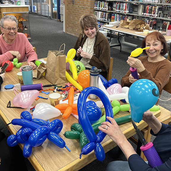 Librarians smiling during balloon twisting teambuilding event.