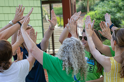 Participants high fiving during an outdoor teambuilding event.